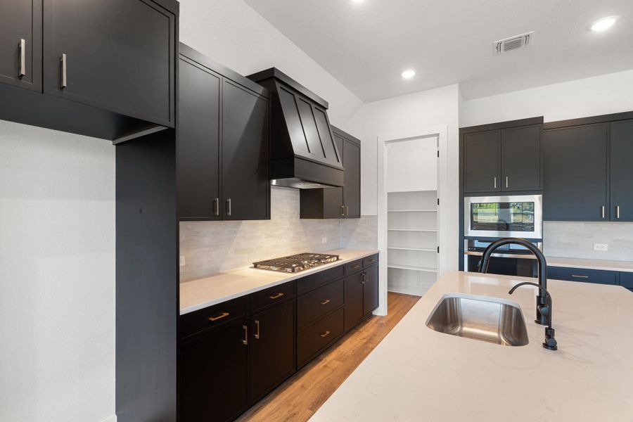 This kitchen features dark cabinetry, bright countertops, and a full suite of modern appliances.