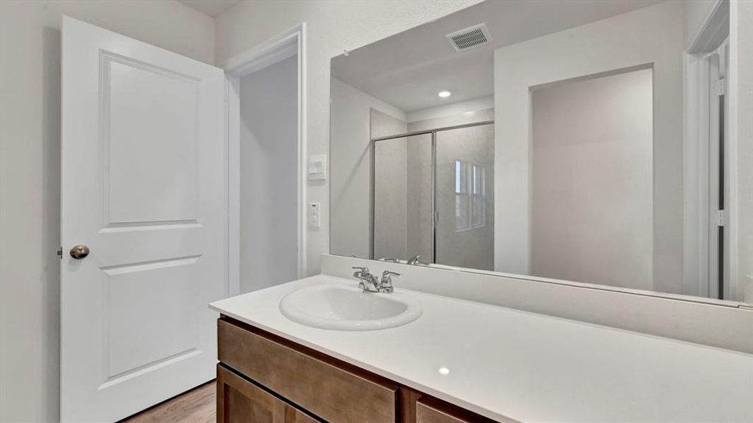 Bathroom vanity featuring an integrated sink, polished chrome faucet, and expansive wall-mounted mirror