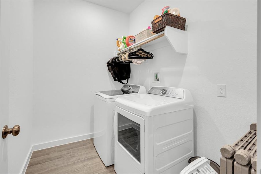 Clothes washing area with washing machine and clothes dryer and light hardwood / wood-style flooring