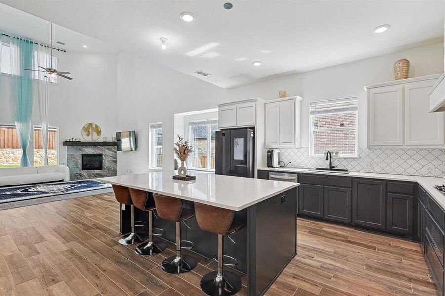 Kitchen with black fridge, white cabinets, a kitchen island, and a healthy amount of sunlight