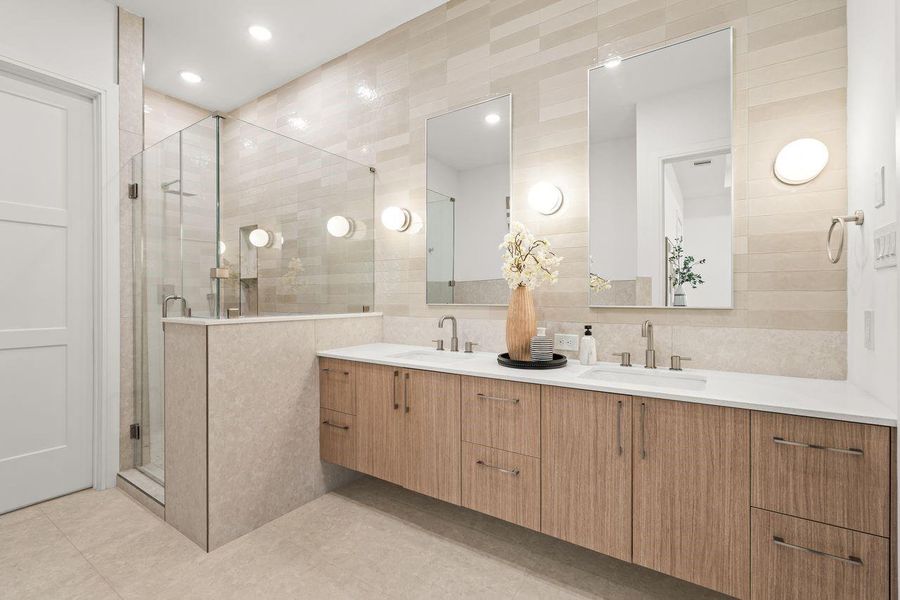 Spa-inspired primary bath defined by floating cabinetry and clean material transitions, where dual vanities, a freestanding soaking tub, and a glass-enclosed shower are arranged with a focus on openness and visual harmony.
