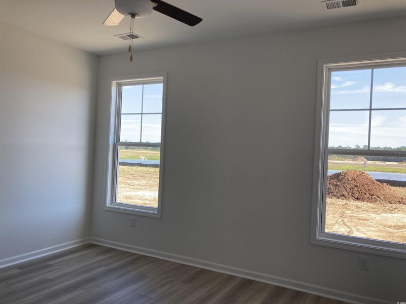 Empty room with dark wood-style floors and a ceiling fan