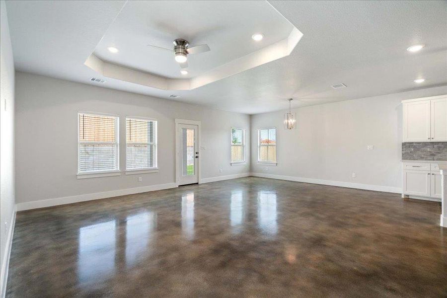 A sun-filled living room with a high tray ceiling, a ceiling fan, and recessed lighting. A sun-filled living room with a high tray ceiling, a ceiling fan, and recessed lighting.