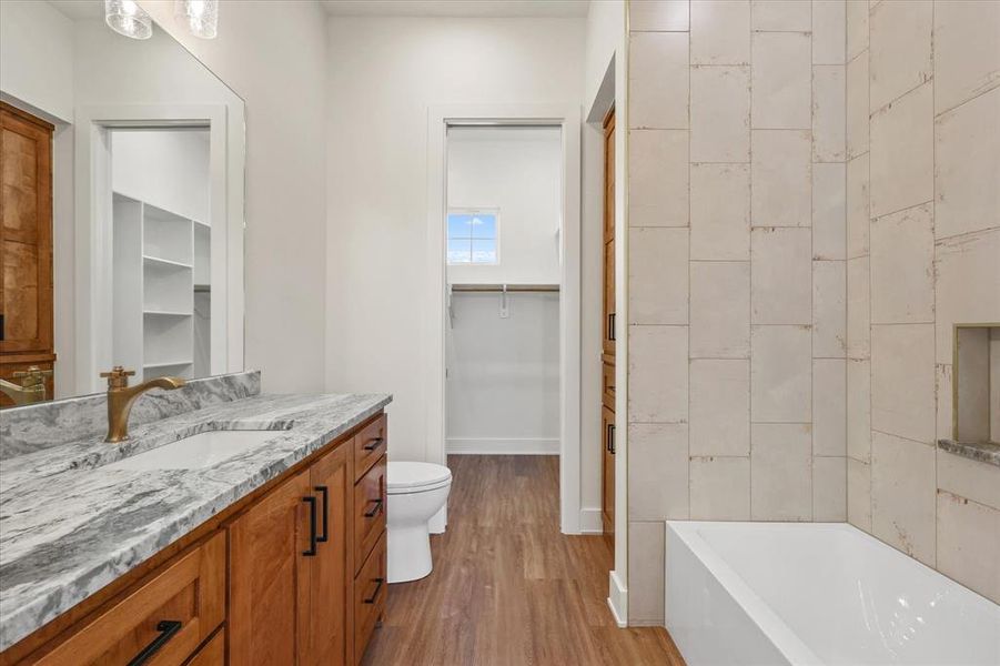 Full bathroom featuring a spacious closet, vanity, and light wood-type flooring