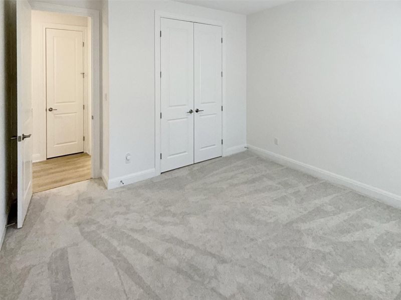 Unfurnished bedroom with light colored carpet and a closet