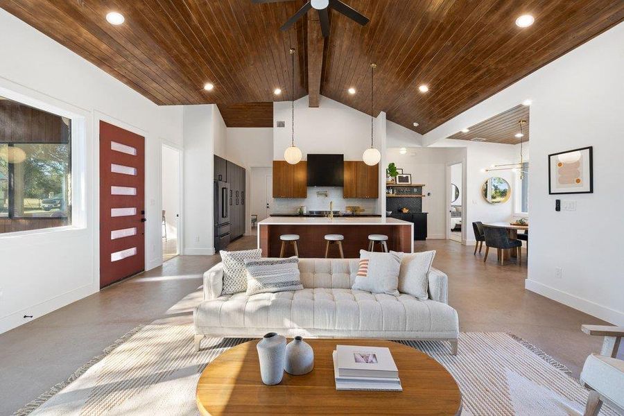 Living room with a ceiling fan, concrete flooring, a wooden ceiling with exposed beams, and high vaulted ceiling