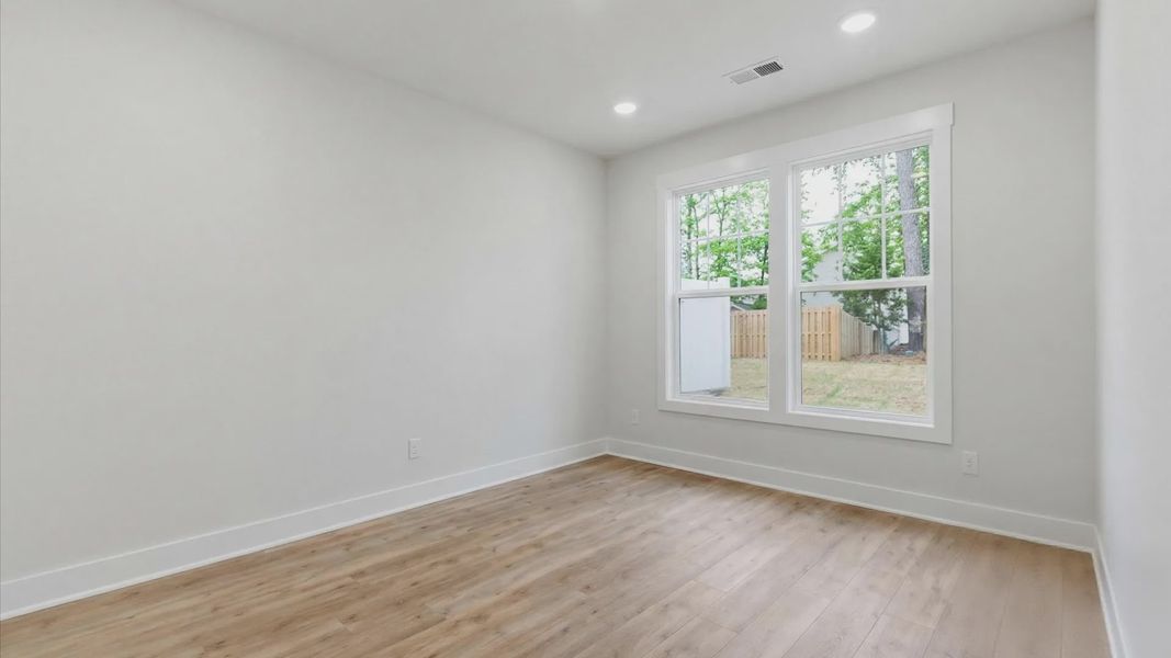 Elegant primary suite with hardwood flooring and superior natural light in this accomplished DRB Homes design