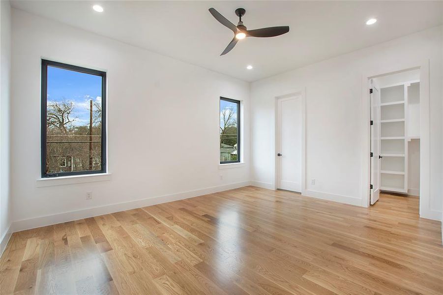 Unfurnished bedroom featuring ceiling fan, a spacious closet, and light wood-type flooring