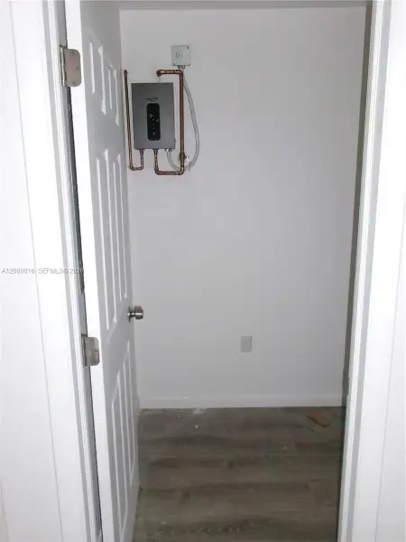 Wall-mounted tankless water heater with copper plumbing lines and wood-finish flooring