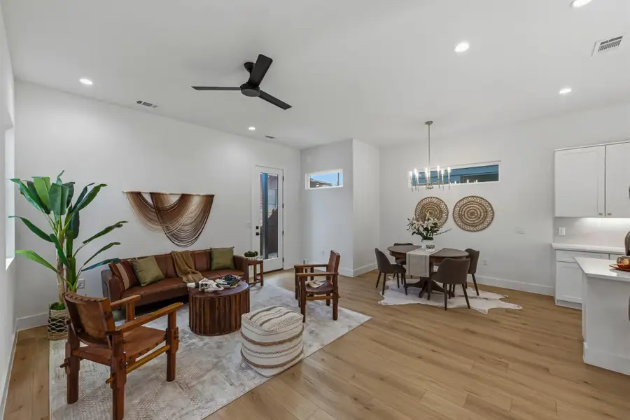Living area featuring light wood finished floors, a ceiling fan, and hanging lights