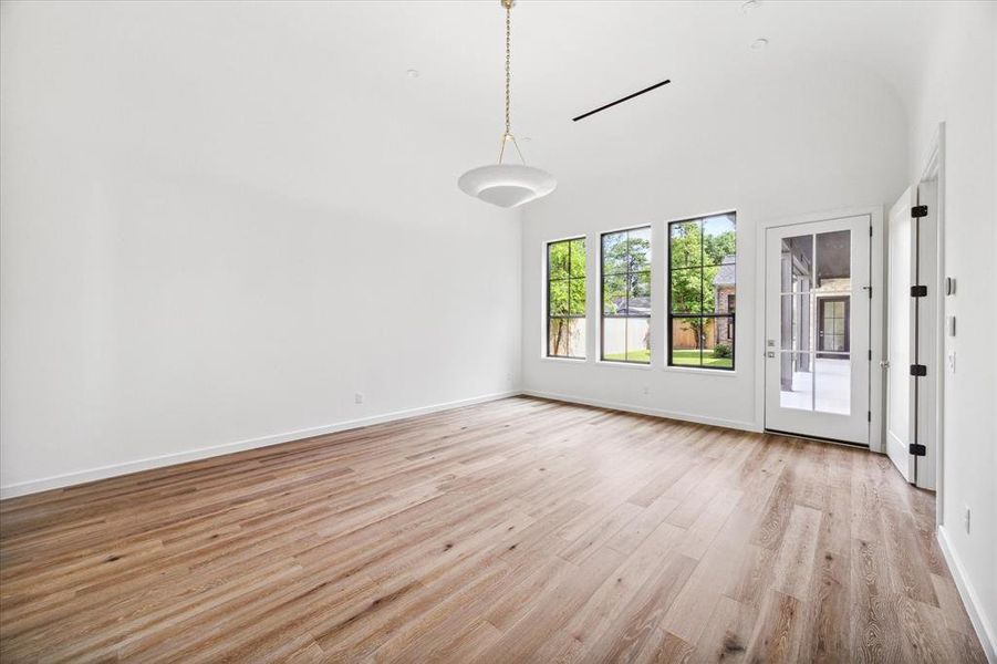 Alternate view of the primary bedroom, featuring large windows overlooking the back yard and a door leading to the outdoor patio with full outdoor kitchen