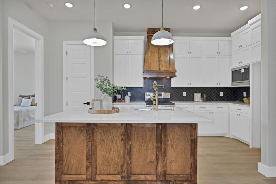 Kitchen featuring stainless steel appliances, a sink, light countertops, light wood-style flooring, and tasteful backsplash Kitchen featuring stainless steel appliances, a sink, light countertops, light wood-style flooring, and tasteful backsplash