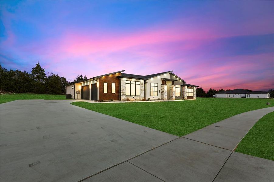 Contemporary home featuring a garage, concrete driveway, and a front lawn