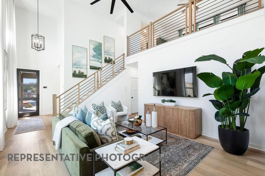 Living area featuring stairs, a high ceiling, wood finished floors, ceiling fan, and a chandelier Living area featuring stairs, a high ceiling, wood finished floors, ceiling fan, and a chandelier