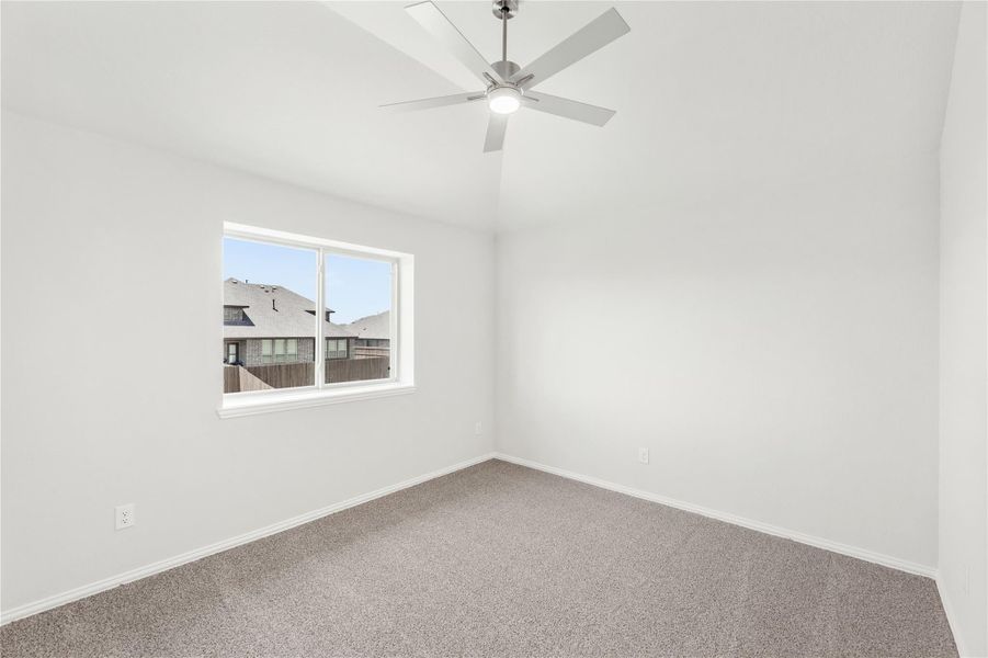 Empty bedroom with gray carpet, ceiling fan, and single window with neighborhood view