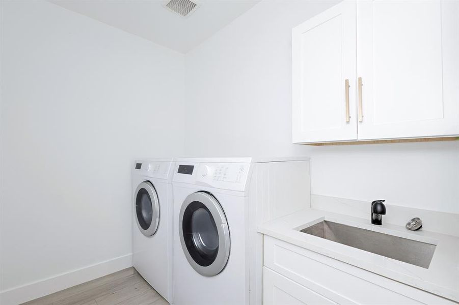 Washroom with washing machine and clothes dryer, cabinet space, and light wood-style floors