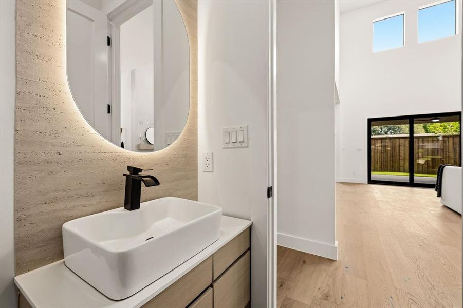 Modern bathroom vanity featuring a rectangular vessel sink, matte black faucet, and an illuminated oval mirror