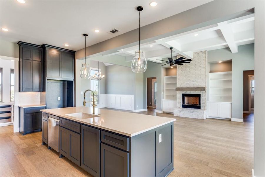 Kitchen with plenty of natural light, light wood-style flooring, beam ceiling, a kitchen island with sink, and hanging light fixtures Kitchen with plenty of natural light, light wood-style flooring, beam ceiling, a kitchen island with sink, and hanging light fixtures