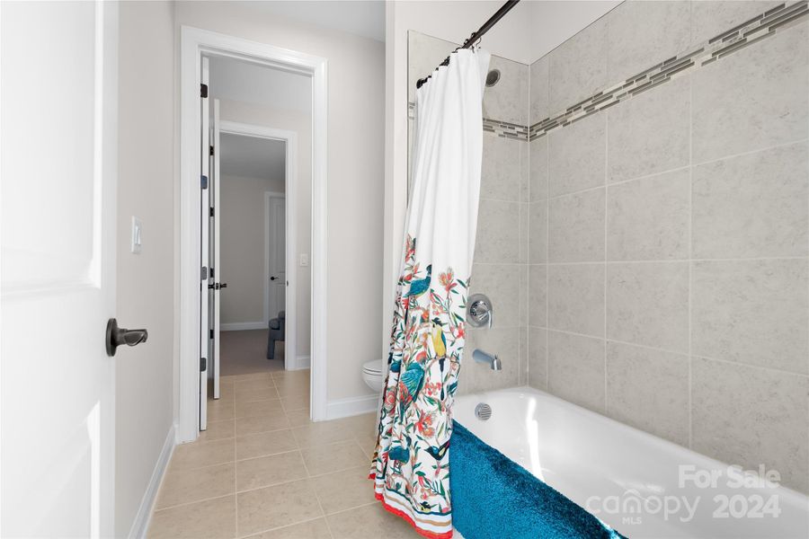 The guest bathroom shared by the two secondary bedrooms has tile floors and a tub with full tile surround and its own Linen Closet