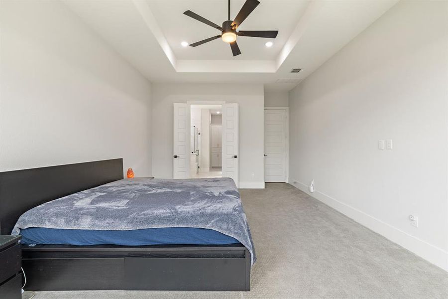 Bedroom featuring a raised ceiling, carpet, recessed lighting, and a ceiling fan