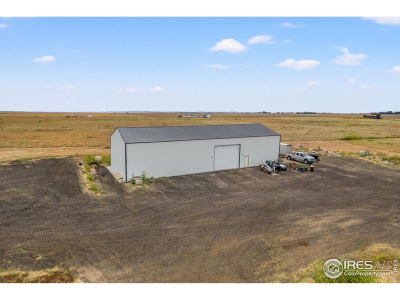 Impressive 100' x 40' shop with oversized overhead door and expansive crushed asphalt lot, providing ample space for equipment, vehicles, or workshop use