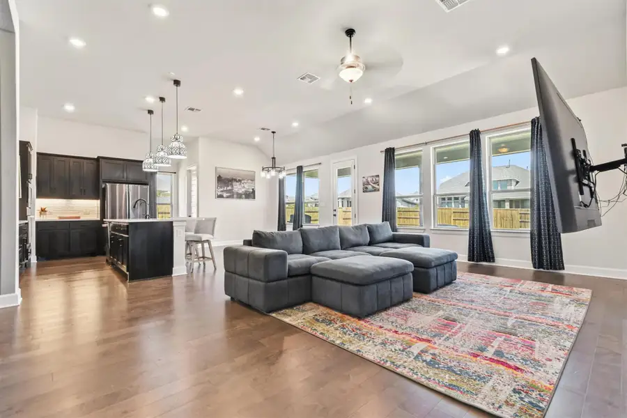 Living area featuring plenty of natural light, recessed lighting, vaulted ceiling, dark wood-type flooring, and a ceiling fan Living area featuring plenty of natural light, recessed lighting, vaulted ceiling, dark wood-type flooring, and a ceiling fan