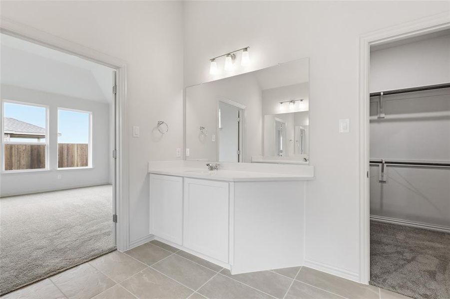 Vanity area featuring a single sink, light-colored countertop, and integrated mirror with overhead lighting
