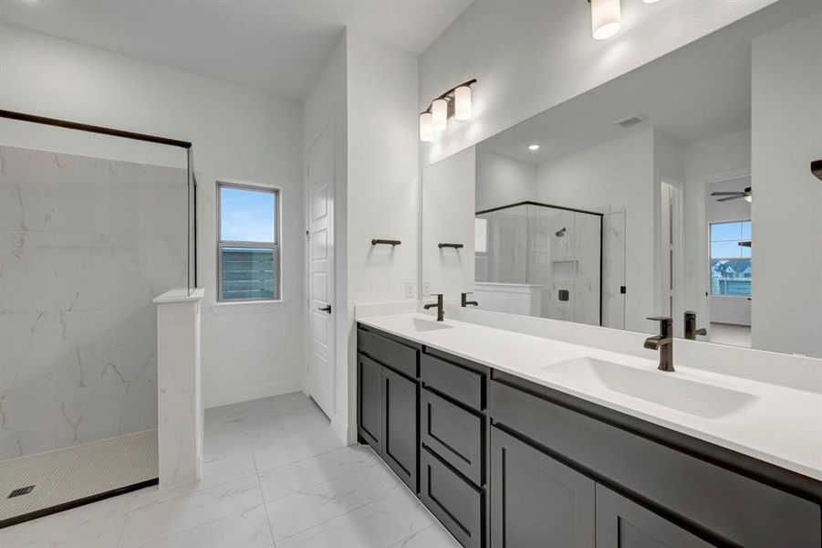 Bathroom with double vanity, a marble finish shower, light marble finish floors, and recessed lighting