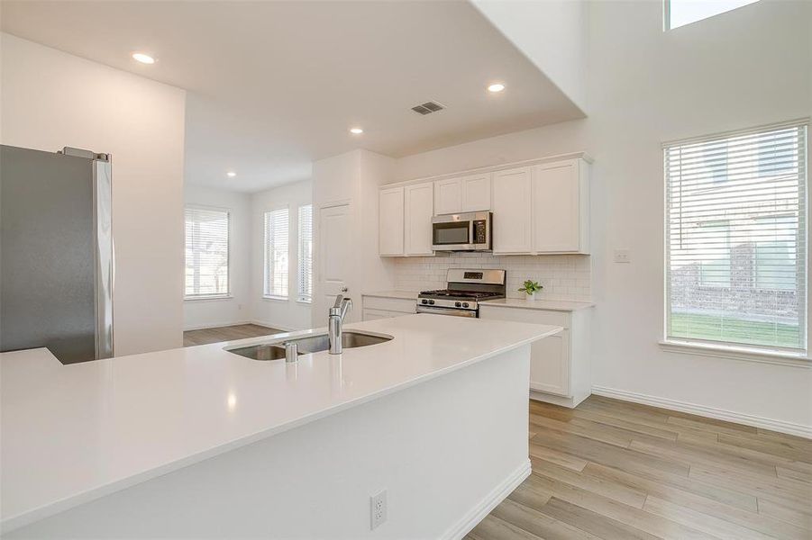 Kitchen with white cabinetry, sink, tasteful backsplash, appliances with stainless steel finishes, and light wood-type flooring