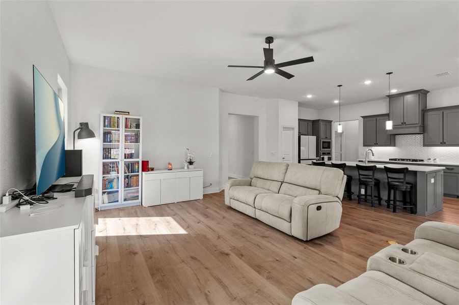 Living room featuring light wood-style flooring, recessed lighting, and ceiling fan