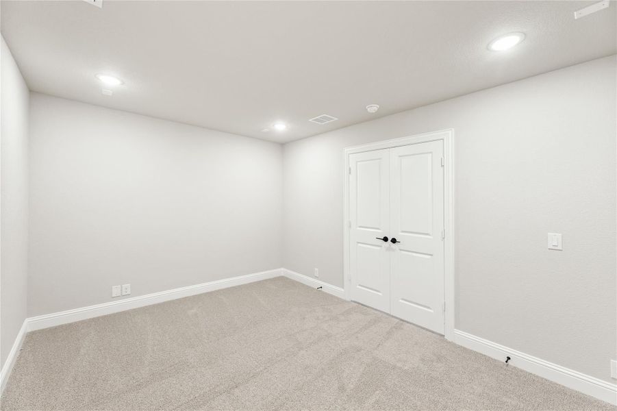 Empty bedroom with gray carpet, white walls, recessed lighting, and double closet doors Empty bedroom with gray carpet, white walls, recessed lighting, and double closet doors