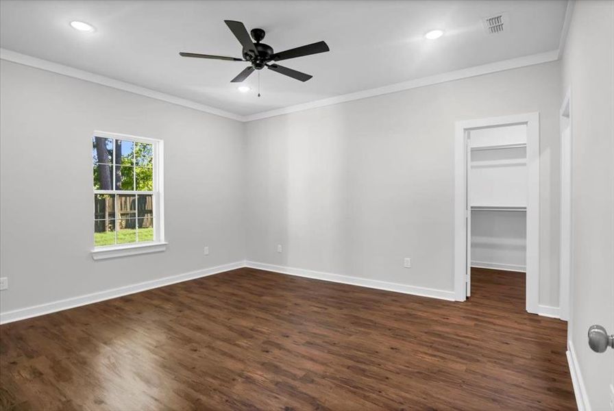 Empty room featuring crown molding, dark wood-type flooring, ceiling fan, baseboards, and recessed lighting