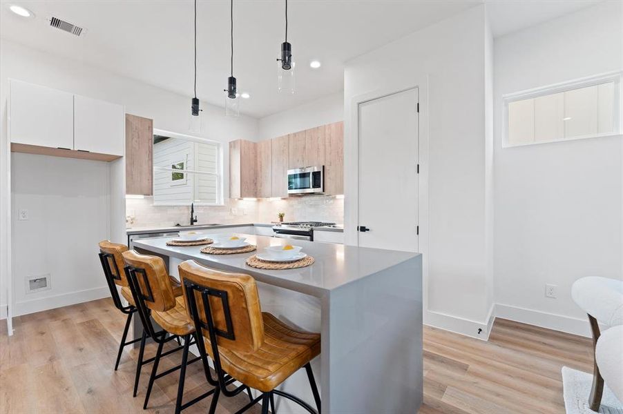 Waterfall island, edge pull cabinetry, and stainless steel appliances throughout.