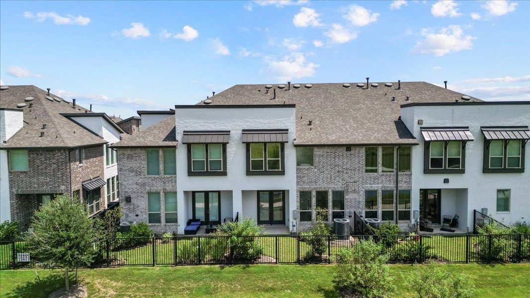 Back of property featuring brick siding, a fenced backyard, and stucco siding Back of property featuring brick siding, a fenced backyard, and stucco siding