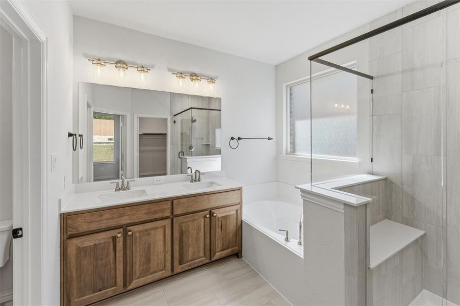 Bathroom featuring a shower stall, a garden tub, double vanity, and a spacious closet