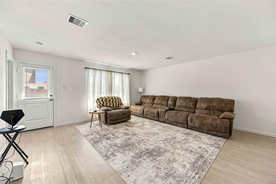 Spacious living room with natural light, featuring a cozy sectional sofa and stylish area rug, perfect for relaxation and entertaining.