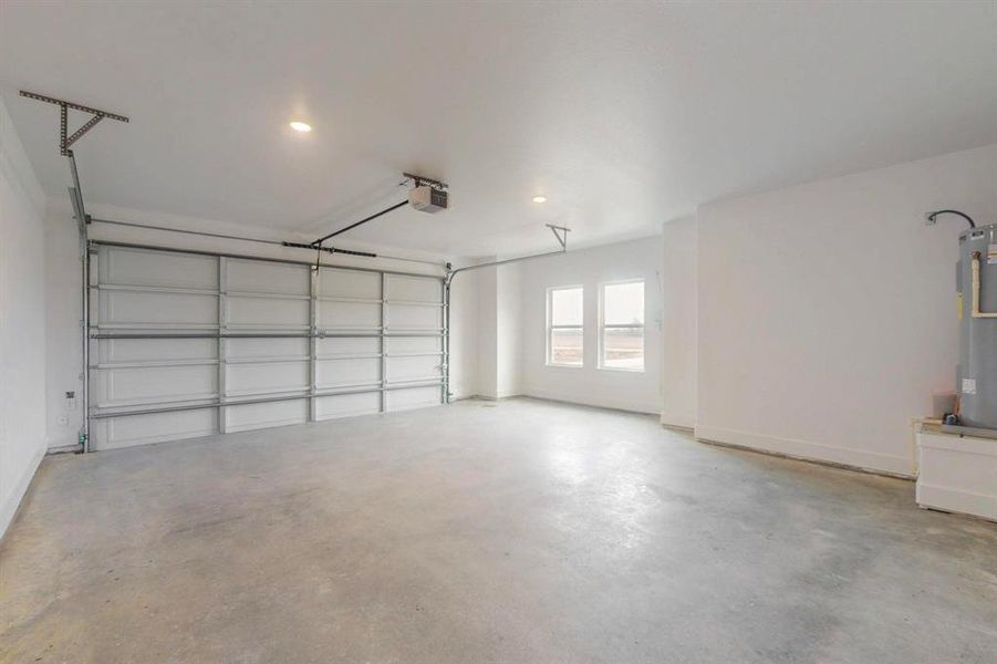 Garage with water heater, baseboards, and a garage door opener Garage with water heater, baseboards, and a garage door opener