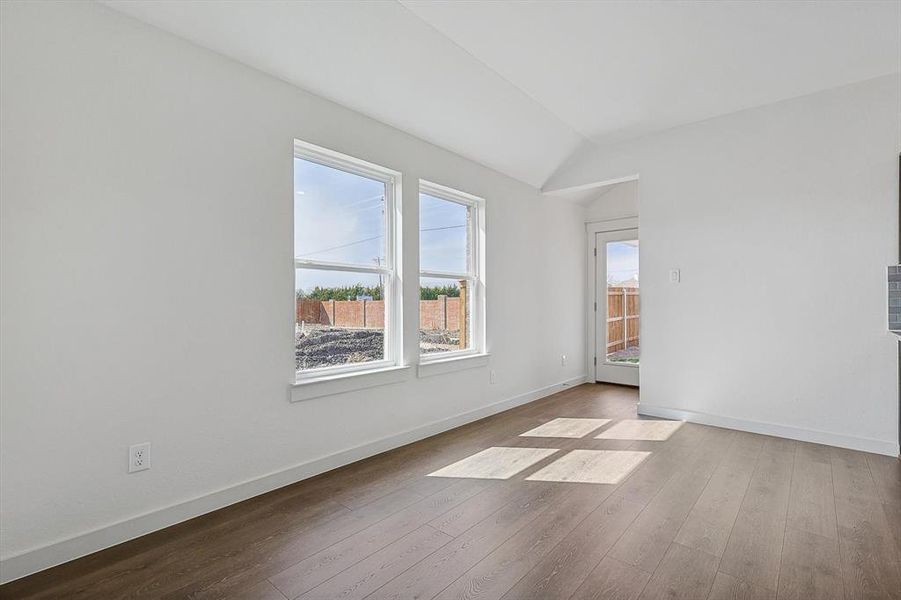 Unfurnished room featuring light hardwood / wood-style floors and vaulted ceiling