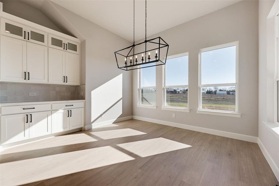 Unfurnished dining area with light wood-style floors and a chandelier Unfurnished dining area with light wood-style floors and a chandelier