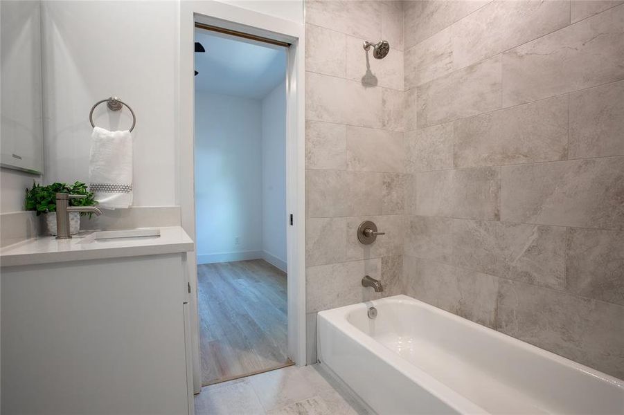 Bathroom with vanity, wood-type flooring, and tiled shower / bath combo