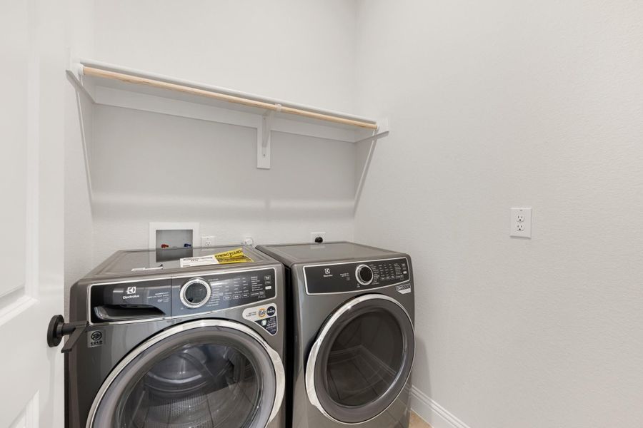 Laundry room with front-load washer and dryer set and a wall-mounted shelf above Laundry room with front-load washer and dryer set and a wall-mounted shelf above