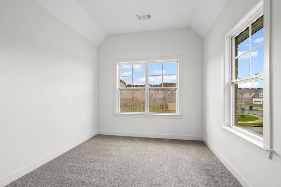 Spare room featuring light carpet, vaulted ceiling, and healthy amount of natural light