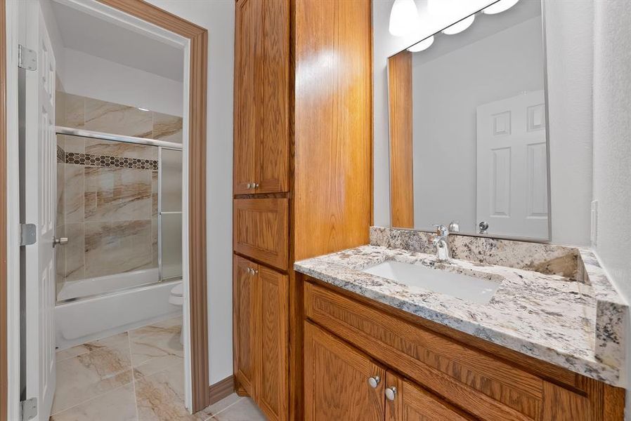 Full bath with vanity, shower / bath combination with glass door, and marble finish floors