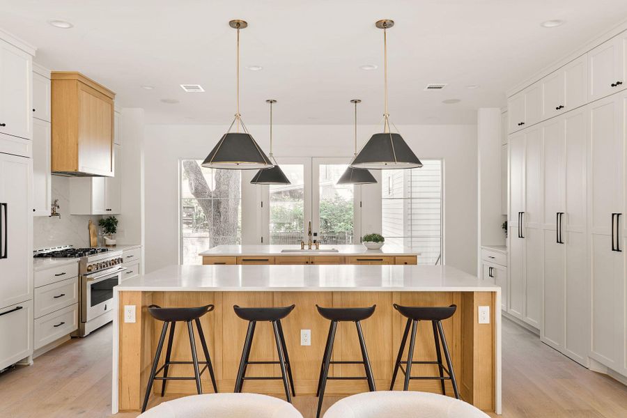 Kitchen featuring a large island with sink, light wood-type flooring, stainless steel stove, a kitchen bar, and recessed lighting Kitchen featuring a large island with sink, light wood-type flooring, stainless steel stove, a kitchen bar, and recessed lighting