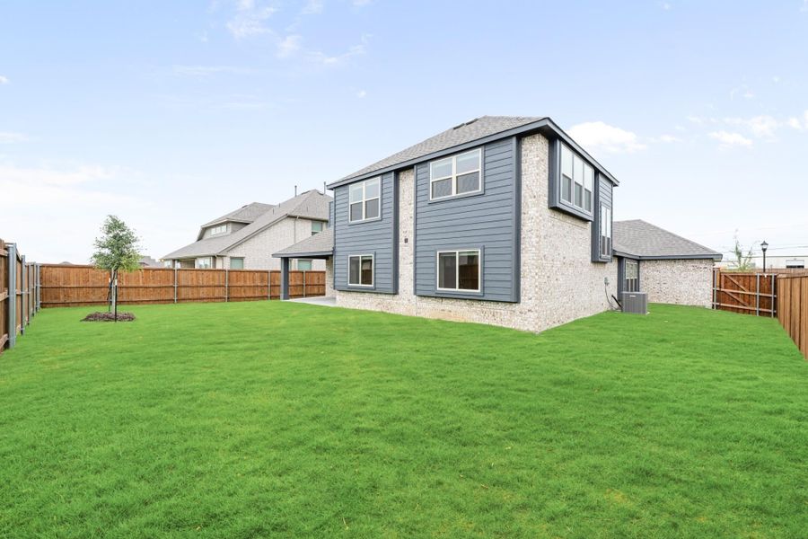 Two-story home with gray siding and brick exterior, large fenced backyard with green lawn Two-story home with gray siding and brick exterior, large fenced backyard with green lawn