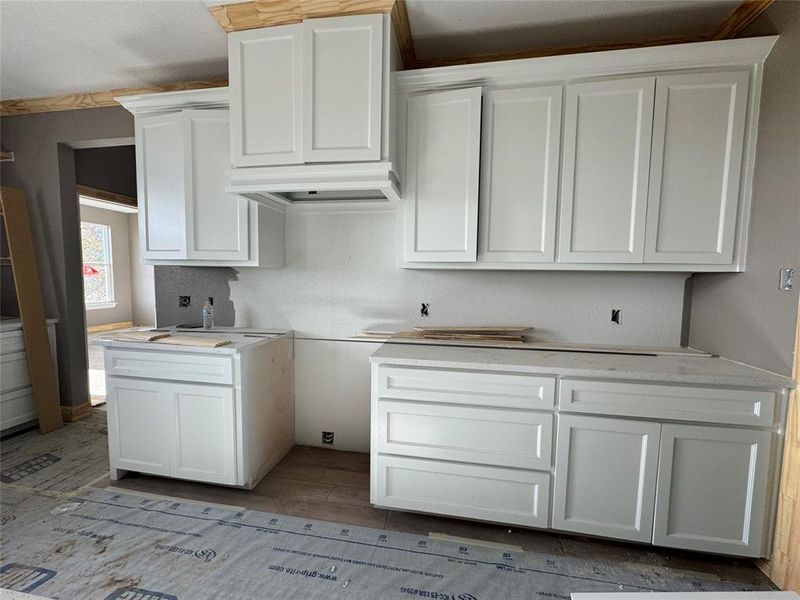 Kitchen featuring white cabinetry and exhaust hood