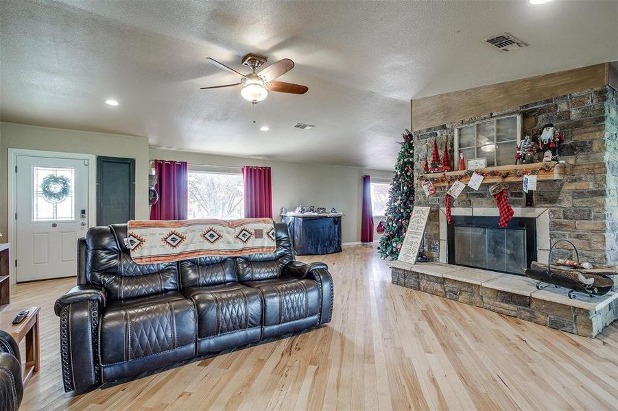 Living room with floor-to-ceiling, stone fireplace with hearth.