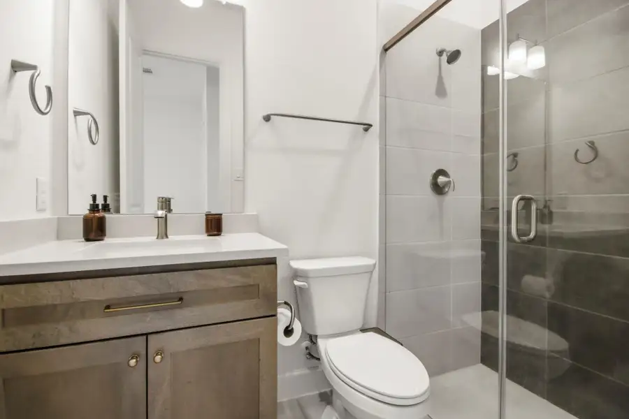 Stylish bathroom featuring a modern vanity, sleek fixtures, and a glass-enclosed shower with elegant tile work.