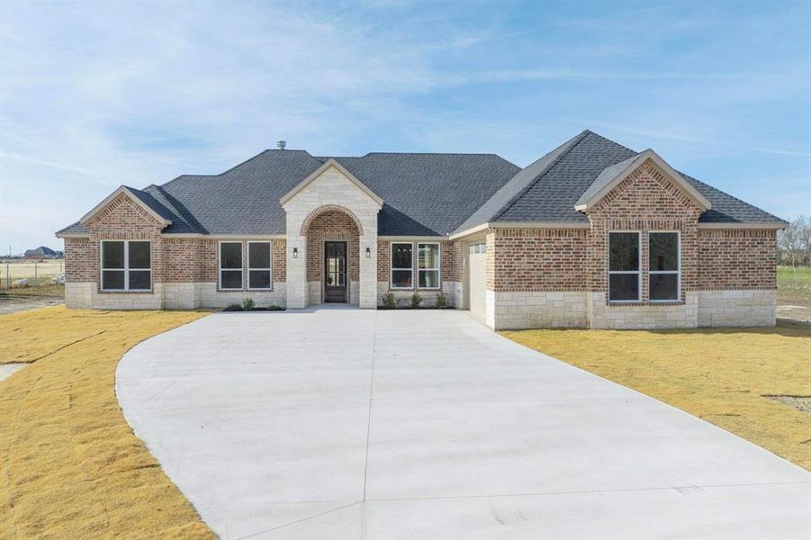 View of front facade featuring a garage and a front lawn