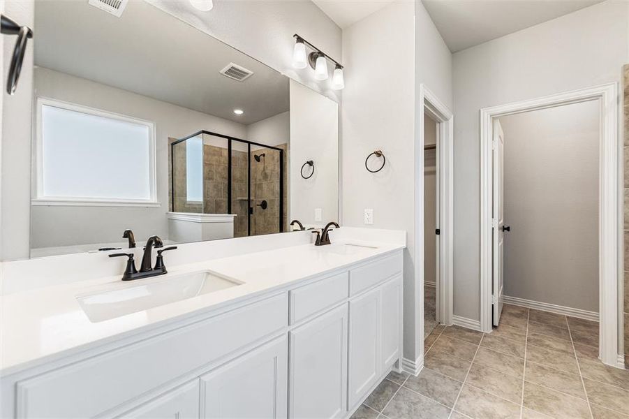 Bathroom featuring double vanity, a stall shower, light tile patterned floors, and a spacious closet Bathroom featuring double vanity, a stall shower, light tile patterned floors, and a spacious closet